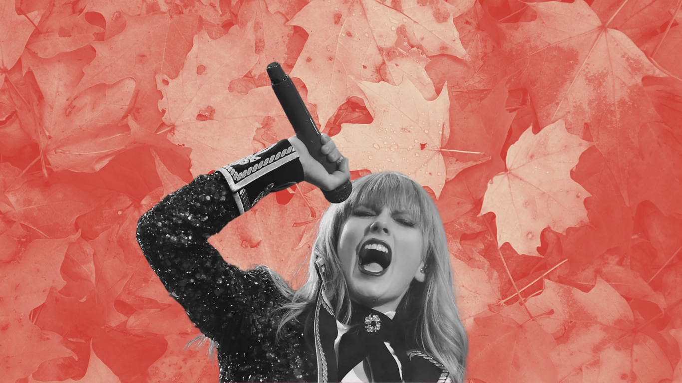 Red-era Taylor swift singing into a microphone against a backdrop of fall leaves
